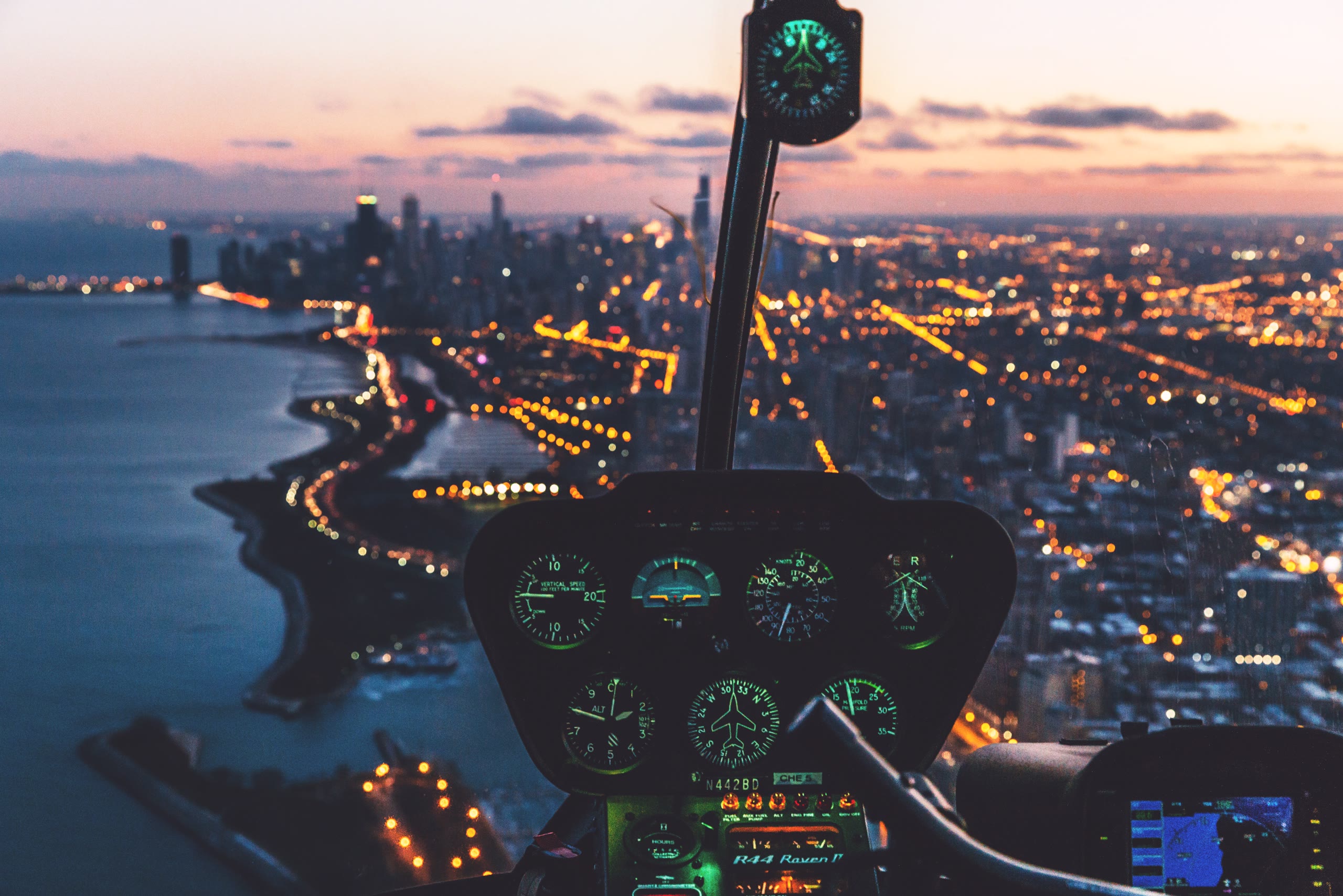 Helicopter cockpit over a city at dusk